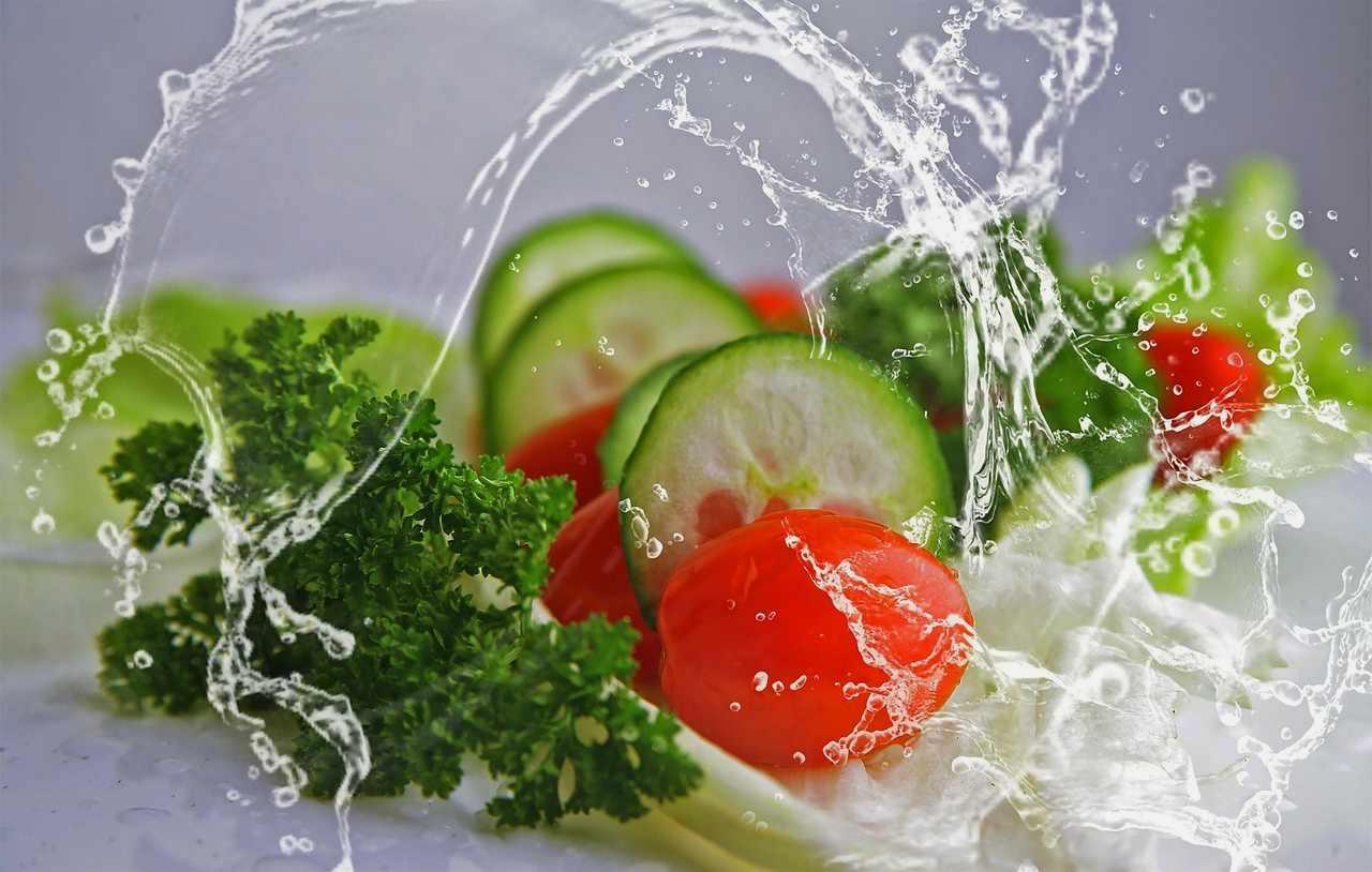 白い花と小さな実がついたパプリカ株に、早朝のジョウロで優しく水を与える場面